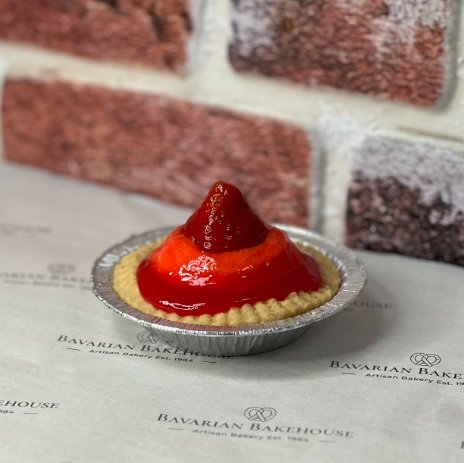 a large strawberry tart on decorative paper with a brick background