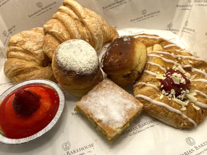 two large flaky croissants, a large strawberry tart, a soft plain scone, a soft fruits scone filled with juicy raisins, apple suare topped with sugar and 2 danish