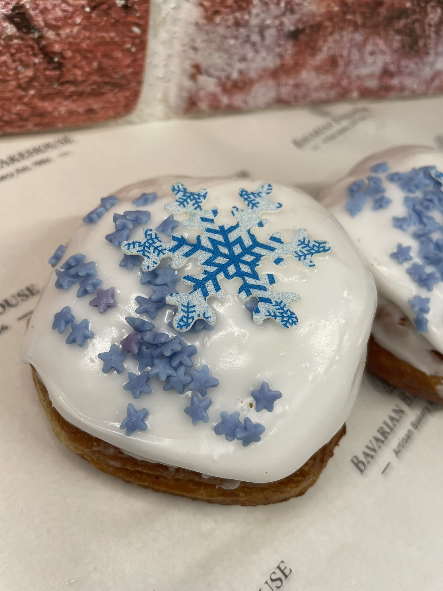vegan doughnut, filled with cinnamon apple, topped with white fondant, blue star sprinkles and an edible blue and white snowflake topper