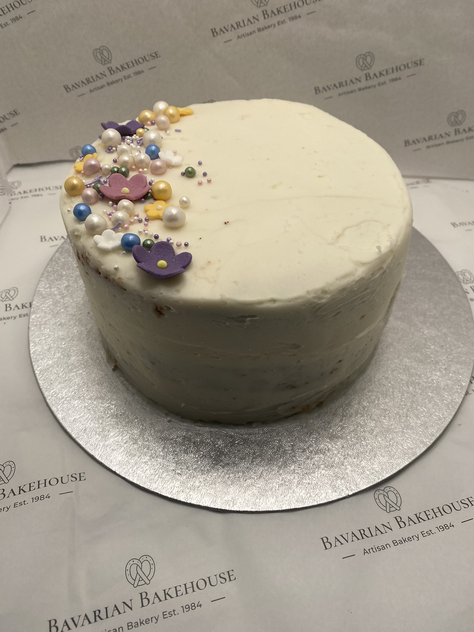 Two moist songe coated in vanilla frosting topped with fondant flowers and sprinkles