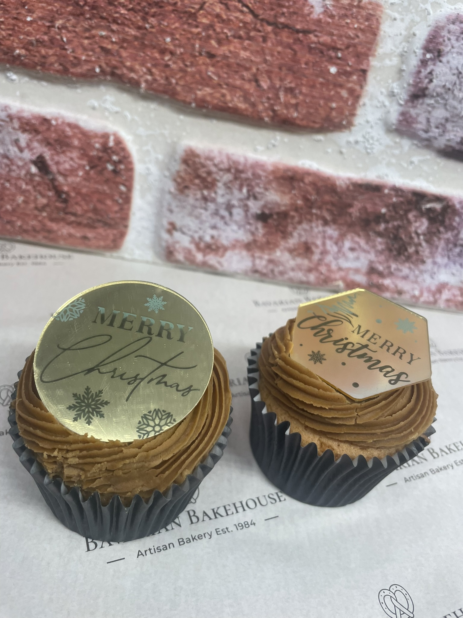 Vanilla Cupckae with gingerbread frosting topped with a gold plastic disc with seasonal messages