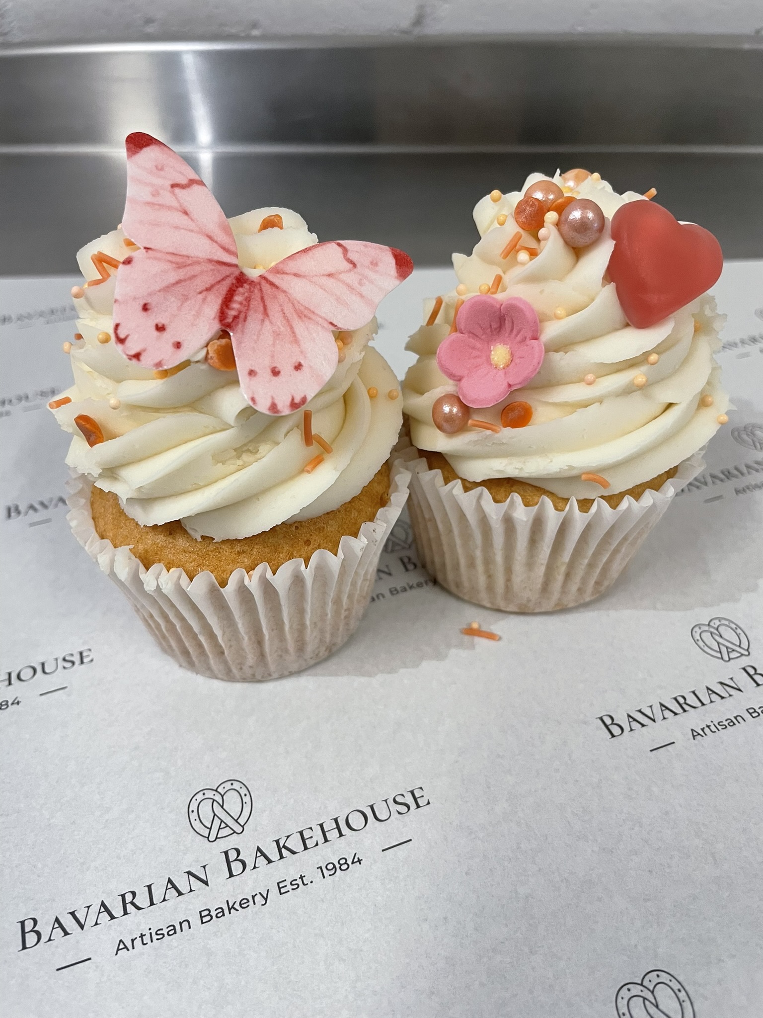vanilla cupcakes topped with vanilla buttercream, edible rice paper butterflies, sprinkles, fondant flowers and haribo hearts