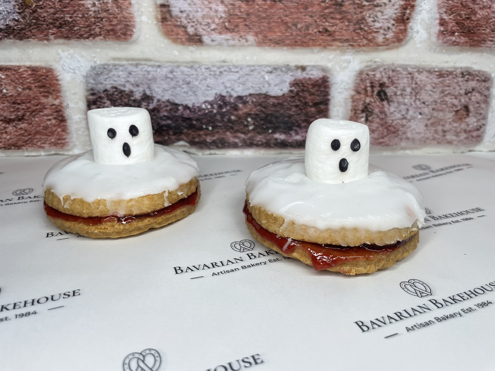 artisan vegan pastry empires filled with fruit jam, topped with white fondant, a vegan marshmallow and iced ghoulish face