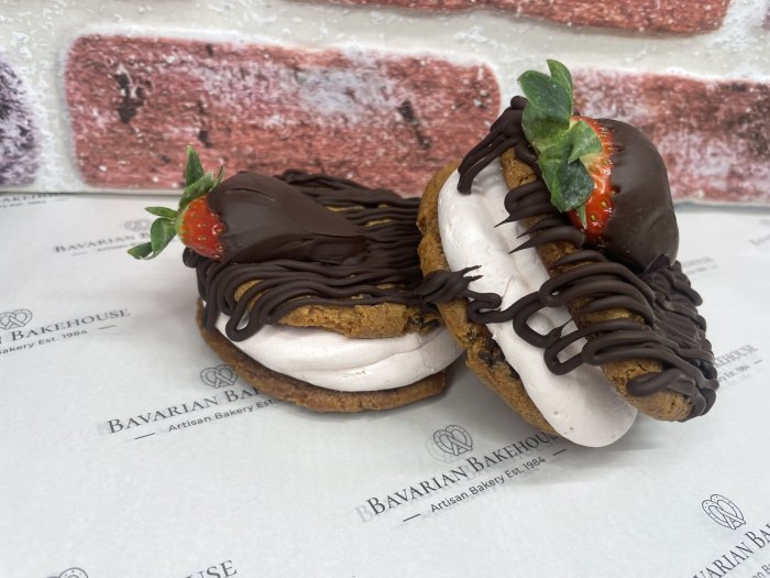 chocolate chip cookies sadnwiched with strawberry cream, topped with a dark chocolate drizzle and a chocolate dipped strawberry