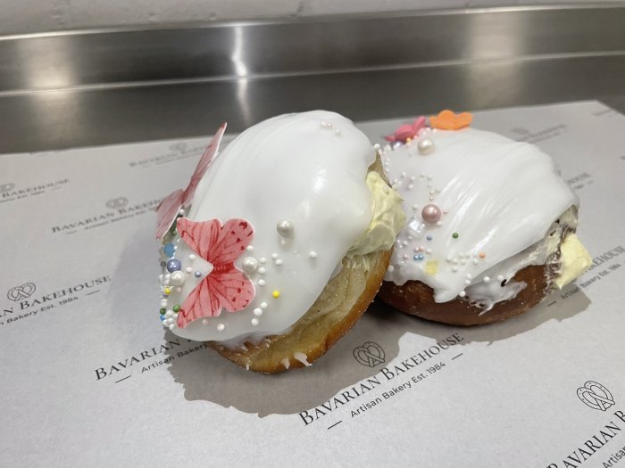 Lemon cream filled soft doughnuts, handcut and fried, dipped in white fondant and decorated with sprinkles, fondant flowers and rice paper butterflies