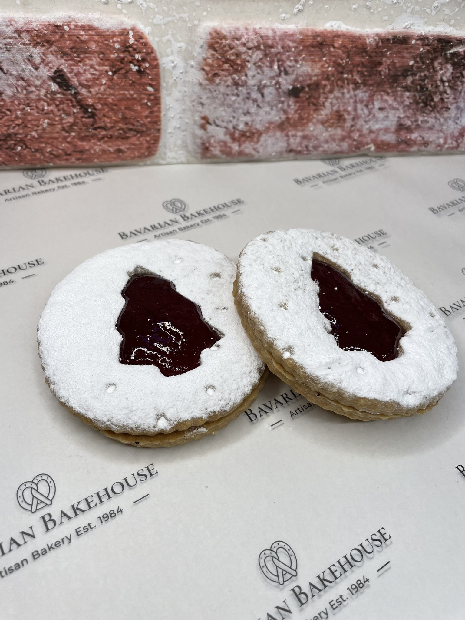 crumbly biscuit sandwich filled with fruit jam, with a tree shaped cut out int he centre and dusted with white powdered sweet snow
