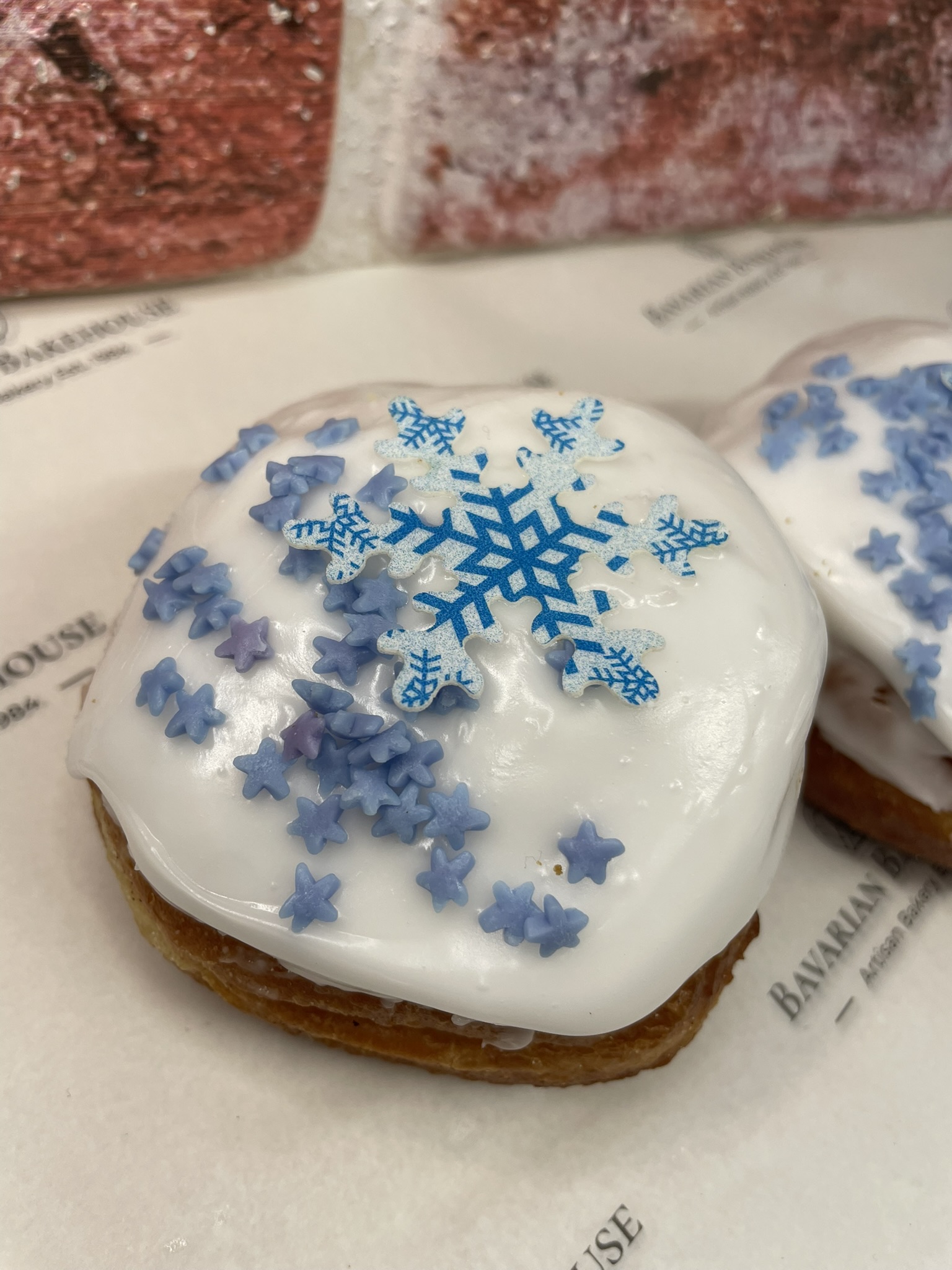 soft doughnut filled with a cinnamon spiced apple filling, topped with white fondant, blue star sprinkles and a blue and white edible snowflake topper